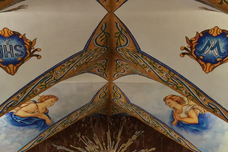 La bóveda pintada de la Basílica: nervaduras doradas, dos ángeles en oración y los monogramas de Jesús y de María.