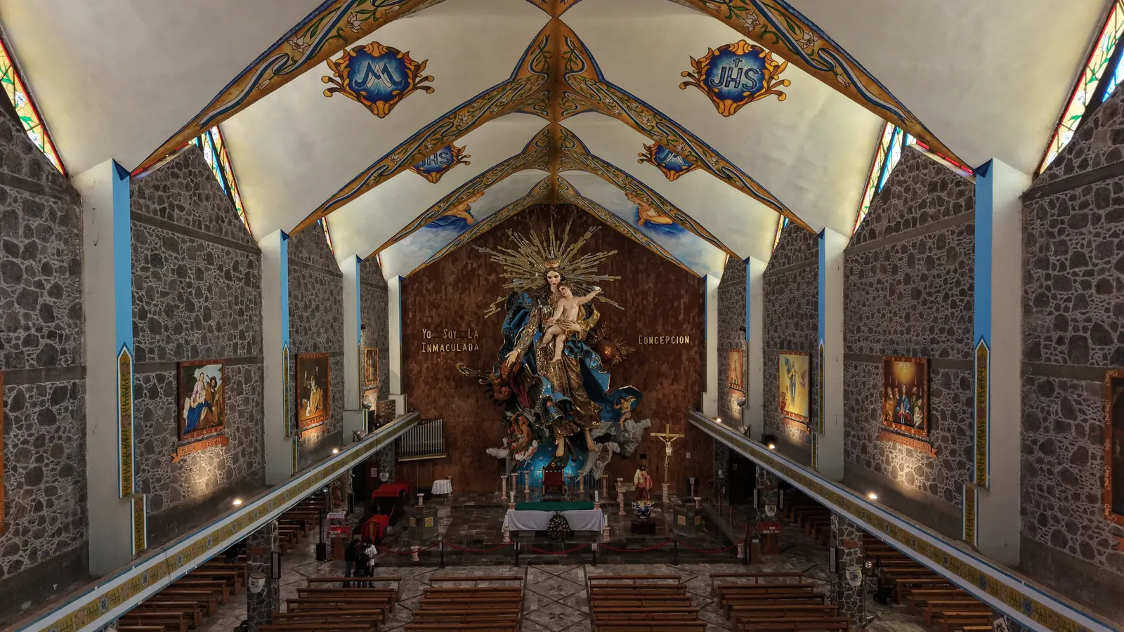 La nave de la Basílica de la Inmaculada Concepción, con muros de piedra y bóveda pintada; al fondo, la gran imagen de la Virgen tallada en madera.