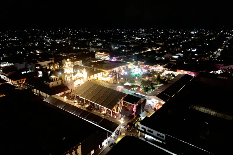 El centro de Chignahuapan de noche, desde el aire: la Parroquia iluminada y las luces del pueblo hasta el horizonte.