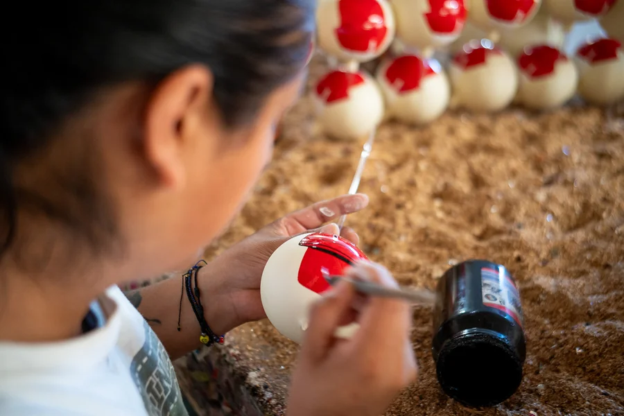 Una artesana decora a mano una esfera con pincel, trazo por trazo