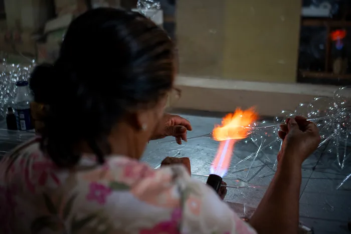 A craftswoman shapes an ornament with the blowtorch in her workshop