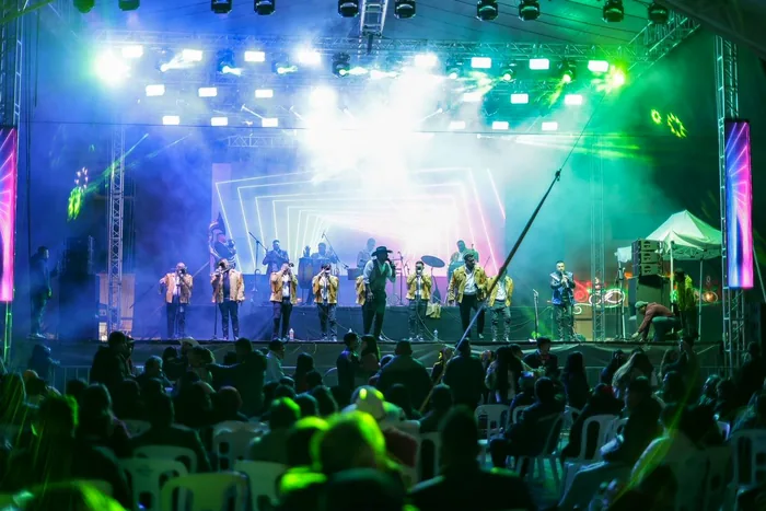 Concierto de noche en Chignahuapan durante las fiestas patrias: una banda en el escenario bajo luces de colores frente al público
