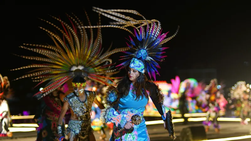 Danzantes con grandes penachos de plumas de colores bailan de noche durante el Festival de la Luz y la Vida