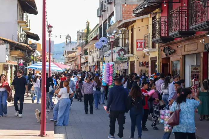 Visitors walking along a downtown Chignahuapan street, among arcades and colorful facades