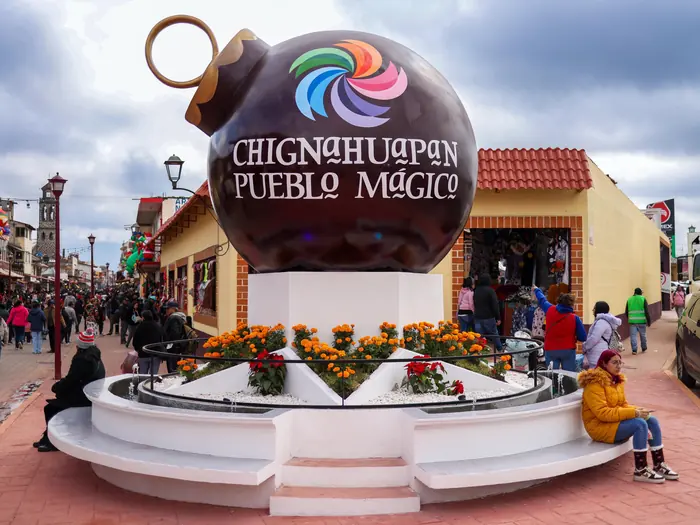 The monumental ornament with the letters Chignahuapan Pueblo Mágico, surrounded by flowers and visitors