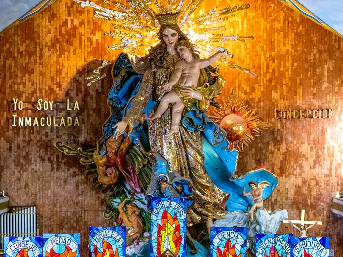 The Virgin of the Immaculate Conception in the Basilica of Chignahuapan: the painted statue holding the Christ Child, with her crown of golden rays, against the gold mosaic wall
