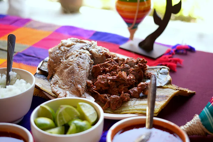 Chignahuapan barbacoa served on a maguey leaf: ribs and shredded meat with rice, limes, consommé and salsa