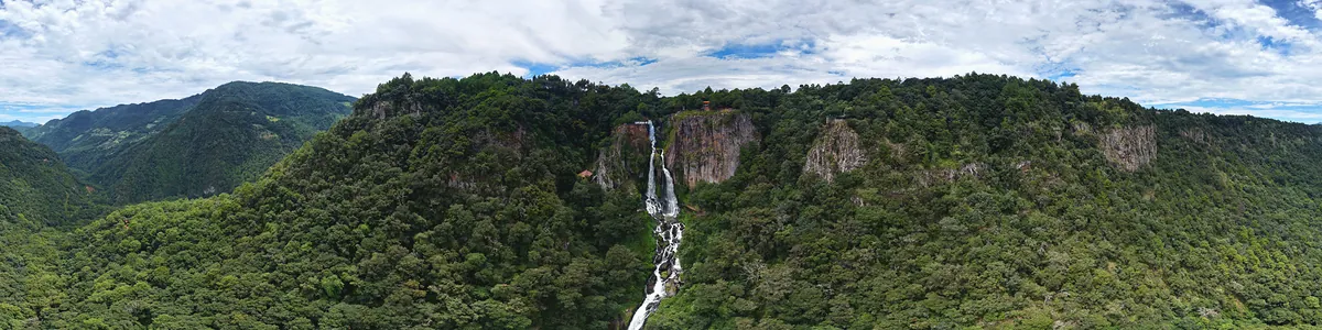 Panorámica del cañón de Quetzalapan con la cascada al centro, rodeada de bosque y sierra.