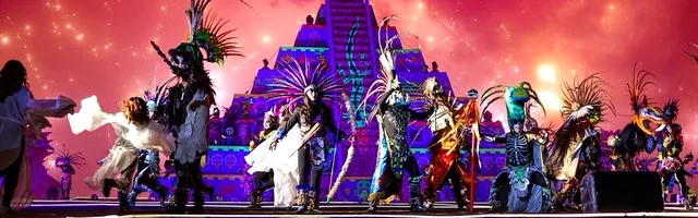 Todo el elenco sobre el escenario frente a la pirámide, bajo un cielo rojo