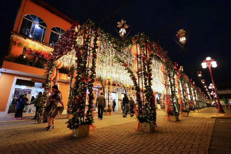 Arcos cubiertos de luces y guirnaldas navideñas sobre una calle del centro de Chignahuapan al anochecer