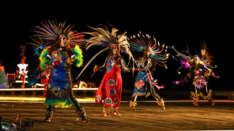 Dancers in feathered headdresses and colorful costumes perform on the lagoon stage during the Festival of Light and Life show