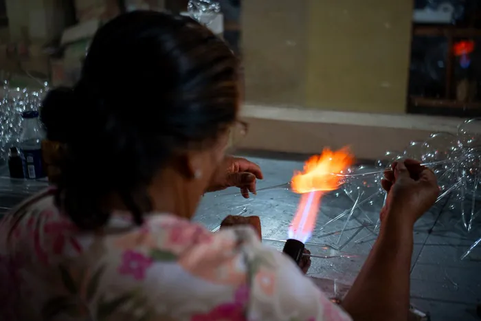 Artesana de Chignahuapan soplando una esfera de vidrio sobre la flama del soplete en su taller