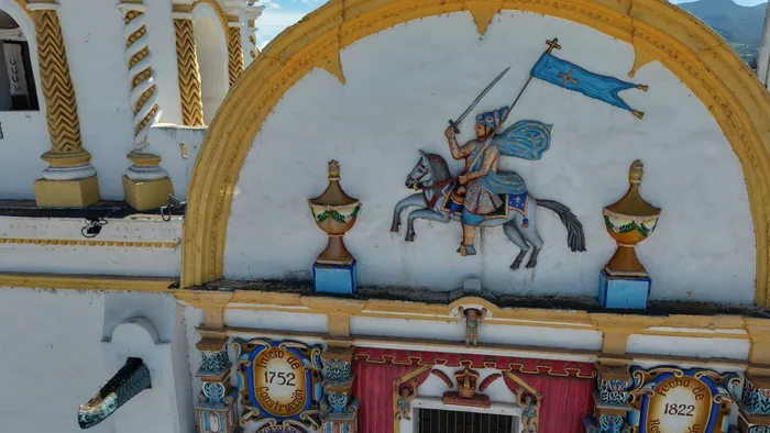 Relieve de Santiago Apóstol a caballo, en lo alto de la fachada de la parroquia, dentro de un arco amarillo.