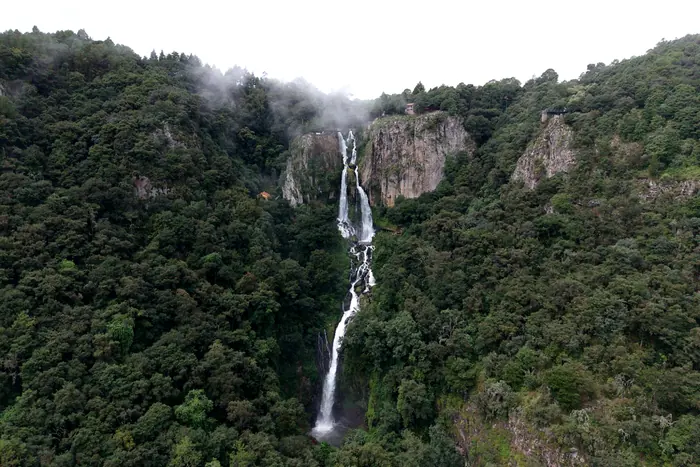 La Cascada de Quetzalapan en toda su caída, al centro del cañón cubierto de bosque