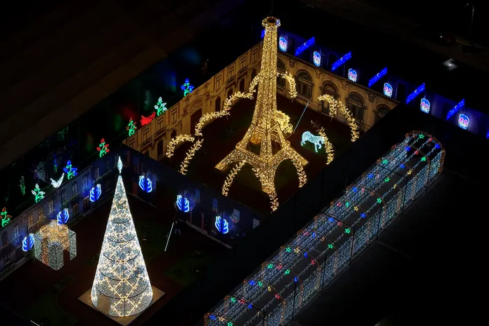 El Mundo Iluminado de noche visto desde el aire: la torre Eiffel de luces doradas al centro, el árbol blanco encendido y el túnel de luces