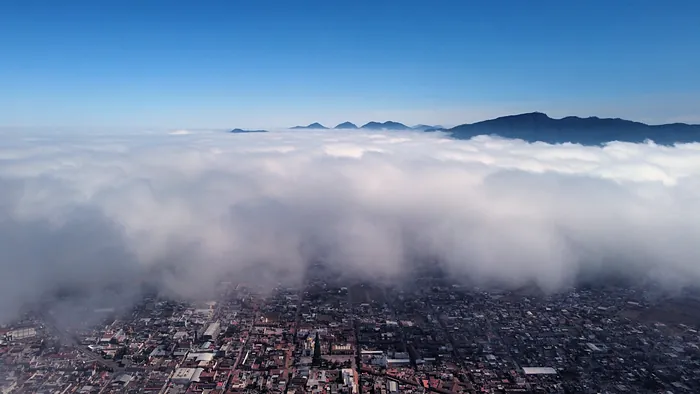The sea of clouds covering Chignahuapan, seen from above, with the mountain peaks rising into the blue sky