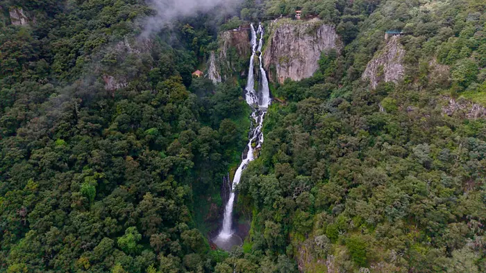 The Quetzalapan Waterfall plunging into the middle of its canyon, between rock walls, forest and mist
