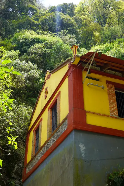 The yellow and red powerhouse of the Quetzalapan hydroelectric plant, in the canyon forest