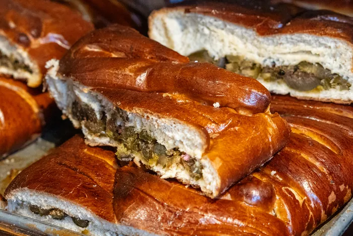 Panes rellenos recién horneados, dorados y brillantes, en la charola de una panadería.