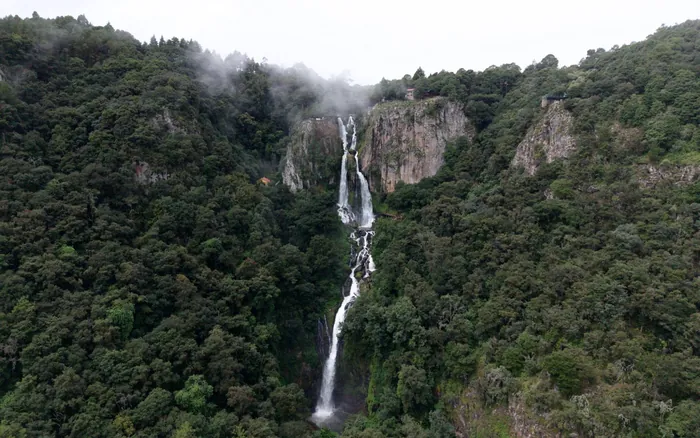 La cascada de Quetzalapan cayendo completa entre paredes de roca y bosque.