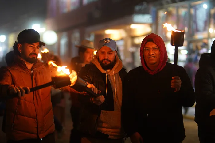 Visitantes caminan de noche con antorchas encendidas durante el Festival de la Luz y la Vida